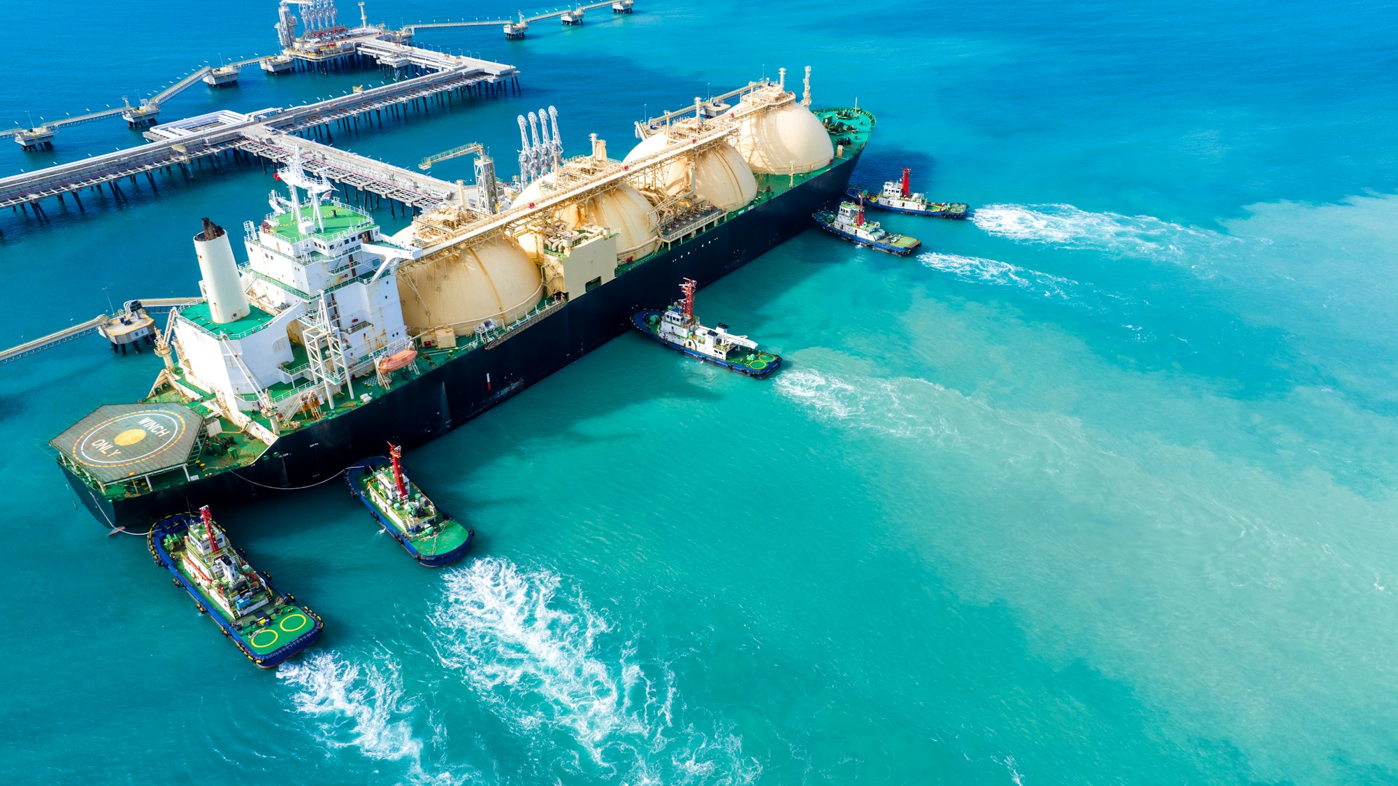 LNG (Liquefied natural gas) tanker anchored in Gas terminal gas tanks for storage.